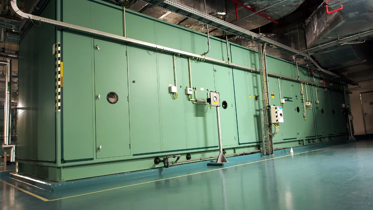 Unidad manejadora de aire de color verde en la sala de máquinas de un edificio