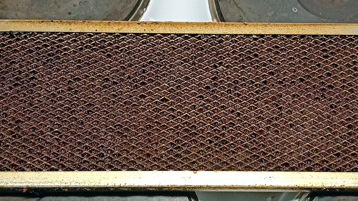 Filtro metálico de campana de cocina cubierto de grasa acumulada