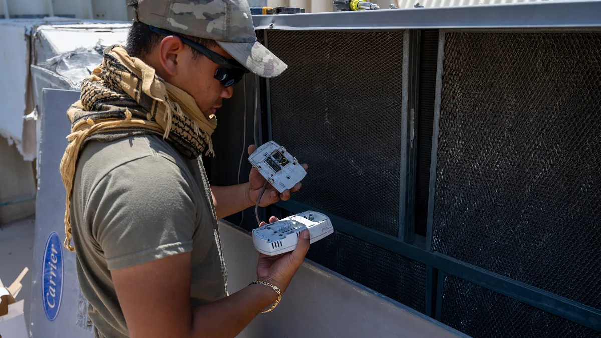Técnico de climatización revisando los controles de una unidad de aire acondicionado comercial